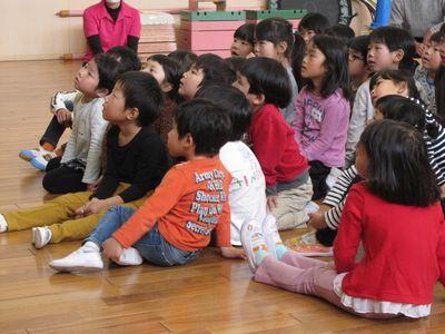 床に座って、前方を見ている子供たちの写真