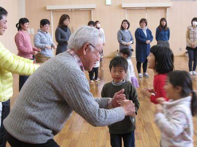 白髪の男性と、両手でグータッチをしている子供たちの写真