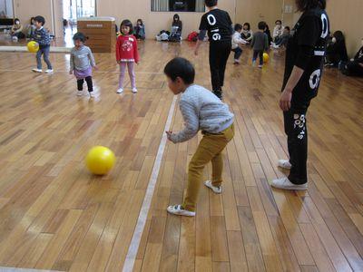 男の子が、線の中にボールを転がし、線の中にいる女の子が見ている写真