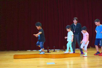 平均台のような板の上をバランスを取りながら歩いている子供たちンお写真