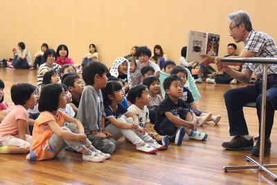 絵本の読み聞かせを座ってい聞いている子供たちの写真