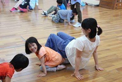 あ母さんが座って手を後ろについて腰を上げその間を子供がくぐっている写真