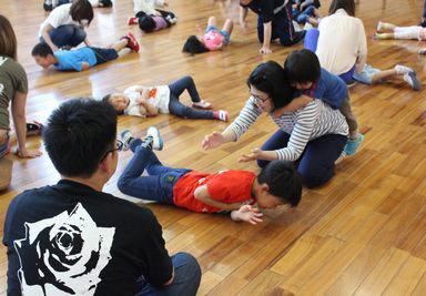 子供がうつぶせに寝転んでお母さんたちが上から押している写真