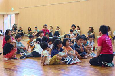 スタッフの方の話を座って聞いている子供たちの写真
