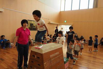 跳び箱の上に乗ってジャンプしようとしている子供の写真