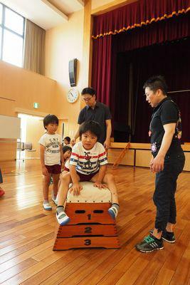 3段の跳び箱にまたがっている子供の写真
