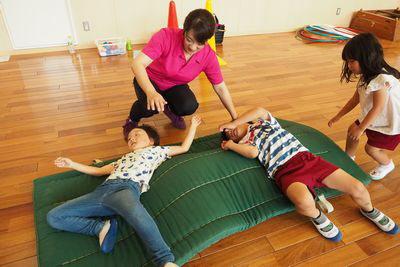 マットの上で寝転んでいる子供たちの写真