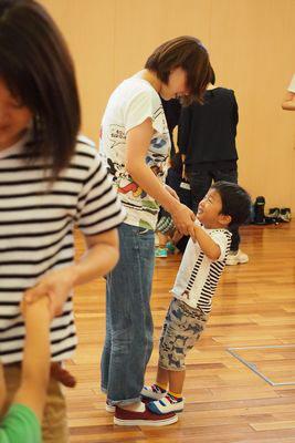 男の子があ母さんと手をつないで足の上に乗っている写真