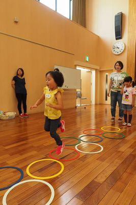 色とりどりのループを床に並べてケンケンパをしている子供たちの写真