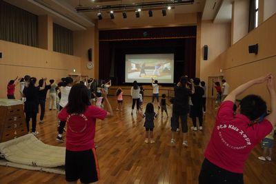 参加者の皆さんがスクリーンを見ながらダンスをしている写真