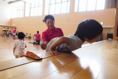 舞台に手をついて飛び上がり乗ろうとしている男の子の写真