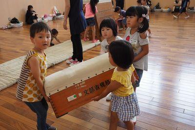 子供4人で一つの跳び箱を運んでいる写真