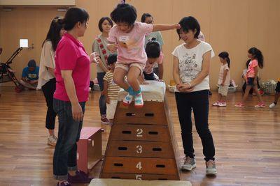 跳び箱の上に登って下へジャンプしている女の子の写真