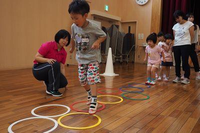 サークルを床に並べてケンケンパをしている子供たちの写真