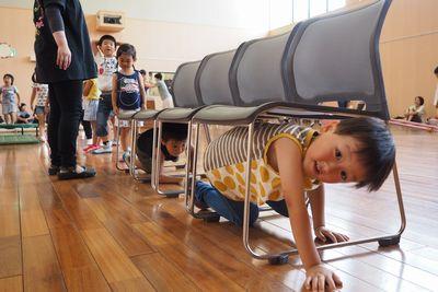4脚の椅子を並べて下をくぐっている男の子の写真