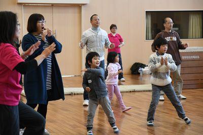 参加者の親子たちが手を叩きながらダンスを踊っている写真