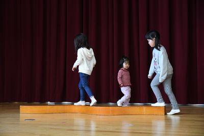 平均台のように伸びた木の上を三人の女の子たちが歩いている写真