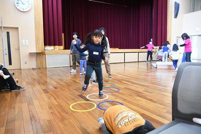 床の上に置かれた輪っかの上を女の子がケンケンパでジャンプしている写真