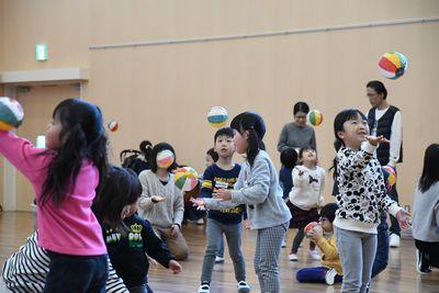 子どもたちが紙風船を手のひらで高く上に投げたりしながら遊んでいる写真