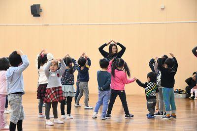 スタッフが山をつくるように手を頭の上にあげていて、子供たちも真似をして手を上に上げている写真