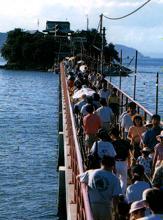 津嶋神社に続く橋を大勢の人が渡っている写真