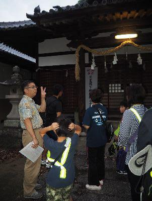 薄暗い神社の境内の前で大人や子供が立っている写真