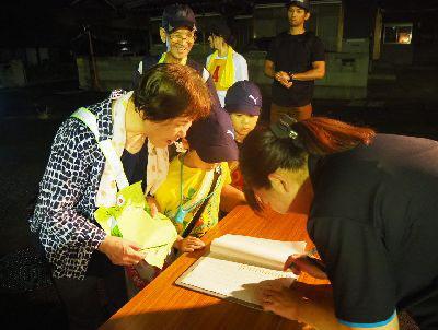 参加された方が順番ずつに並び、スタッフの女性がノートに記載している写真