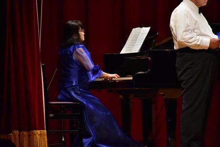 青のドレスを着た山神 千恵子さんがピアノを演奏している写真