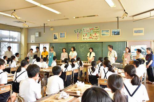 黒板の前に1列に並び挨拶をしている受講生の方々と席についている生徒達の写真