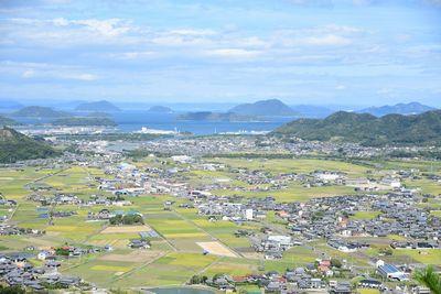 田んぼや家屋、遠くの海や島々が写っている写真