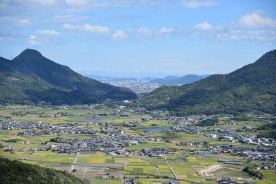 田んぼや家屋、他の山々が見える山頂からの写真