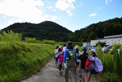 リュックを背負い山へと向かって歩いている子供たちの写真