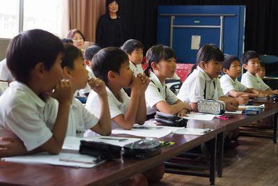 机に座って見学している子供たちの写真