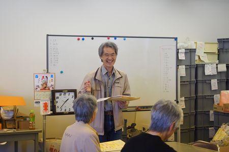 ホワイトボードの前で講師の先生が笑顔で資料片手に説明をしている写真