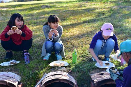 出来上がったクッキーを座って食べている女の子3人の写真