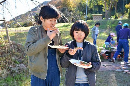 出来上がったピザを食べている女の子2人の写真