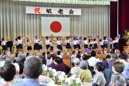 ステージでボンボンを持って踊っている小学生20名ほどの写真