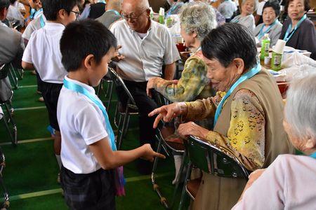 高齢者とじゃんけんをして触れ合っている子供たちの写真