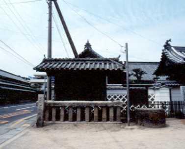 道路沿いに建てられている木造本瓦葺きの辻の札場の写真