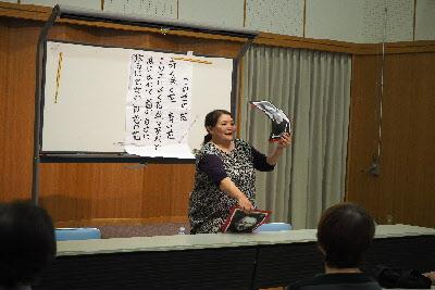 大浦 美樹先生が前に立って、俳優の写真が載った紙を参加者達に見せてクイズを出している写真