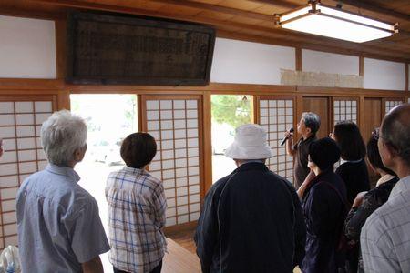 部屋に飾られた年代物の奉納額の説明を聞いている参加者の人達の写真