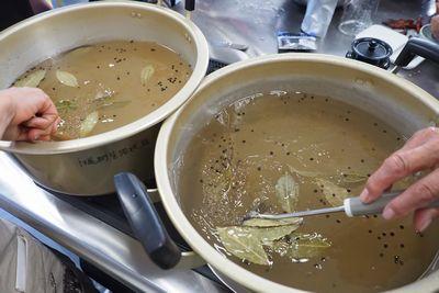 仁尾酢と葉っぱや黒い粒の香辛料が入れられた鍋を混ぜている写真