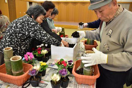 竹の中に段ボールに入った土をすくって入れている写真