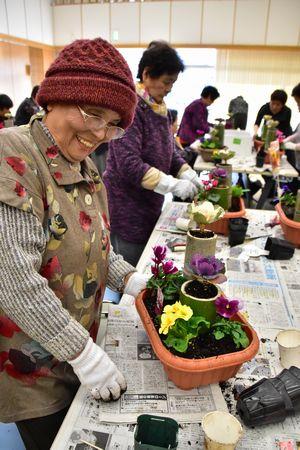 プランターに5種類の花を植えて笑顔の女性の写真