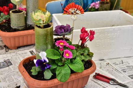 プランターに2本の長短の竹、ピンクや白や紫など5種類の花が飾られている完成写真を左斜めから撮った写真