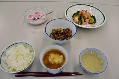 左下から主食、かぶらむし、お茶、中央に野菜の佃煮風、左上からイチゴゼリー、エビとブロッコリーの蒸し煮が並べられてある写真