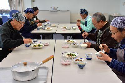 テーブルに座り完成した料理を食べている参加者たちの写真