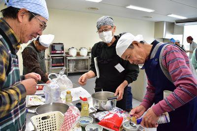 1人の男性参加者が計量スプーンを使い調味料を測っている様子を2人の男性参加者が見ている写真