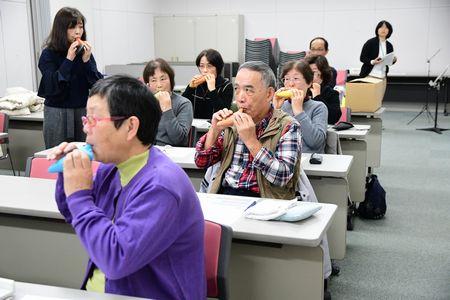 参加者達がオカリナを口に当てて吹いている様子の写真