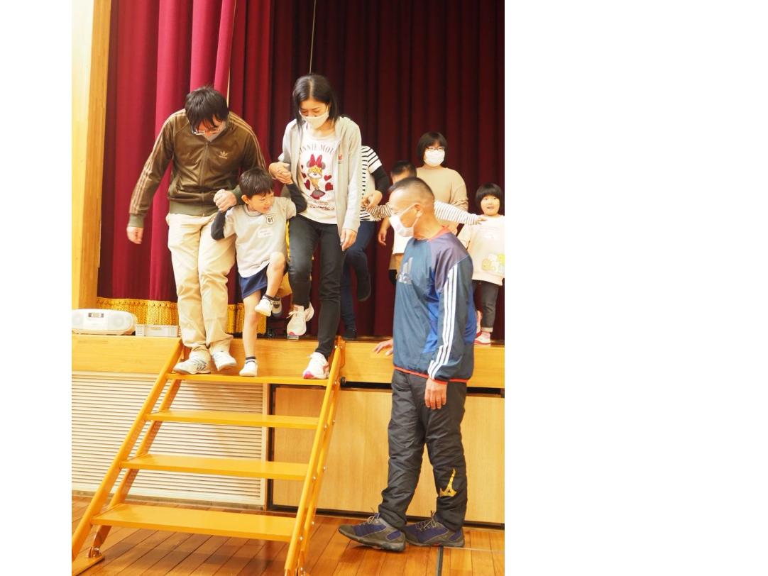 手をつないで階段を下りる父母子